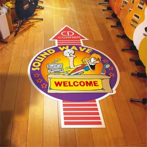 A cartoon floor sign at a music store that says welcome