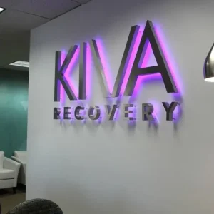 metallic looking 3d letter sign with purple halo lighting above the reception of office