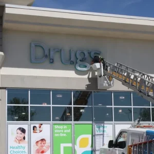 sign repairer on a bucket truck removing a sign for a drugstore
