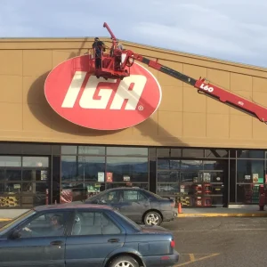 sign technician on a bucket truck repairing a large grocery store sign