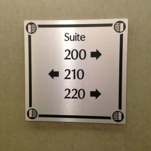 A sign plate that shows the suite numbers and directions in a hotel.