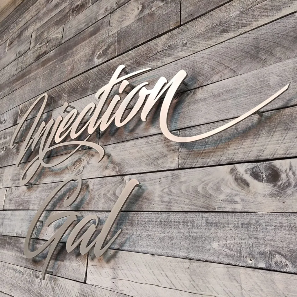 Silver 3D letters installed on wood looking wall.