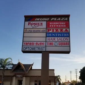 A pylon sign with a variety of businesses for a strip mall.