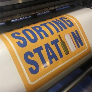 A large printer in the process of printing on a roll of vinyl.