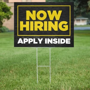 A yard sign that says "Now Hiring"