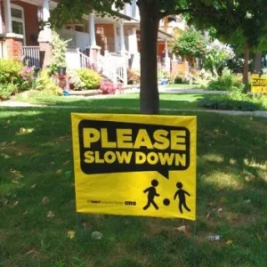 A yard sign that says "Please Slow Down"
