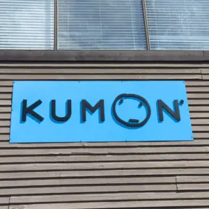 Black corporate logo in 3D letter installed on blue sign board on the side of a building