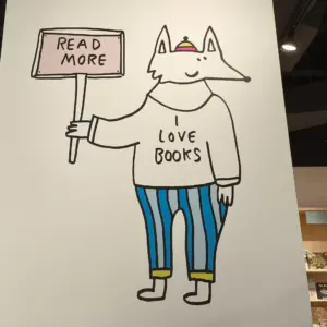 cartoon dog graphics wearing a shirt that says I love books and holding a sign that says read more